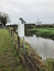 Monitoring kiosk with a solar panel mounted on top installed on the side of a riverbank